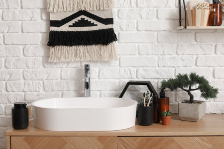 Sink bowl, cup with toothbrushes, houseplant and bonsai tree on wooden cabinet in bathroomの写真素材