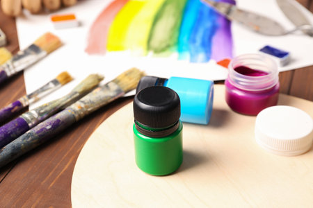 Jar of green gouache paint with artist's supplies on tableの写真素材