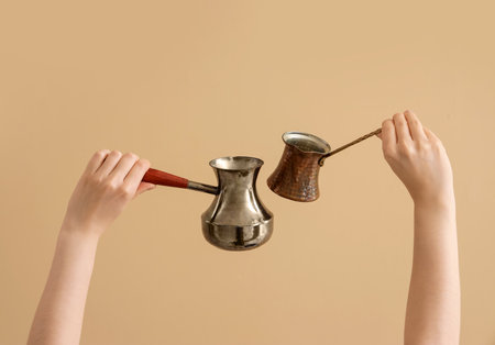 Female hands holding jezve on brown backgroundの写真素材