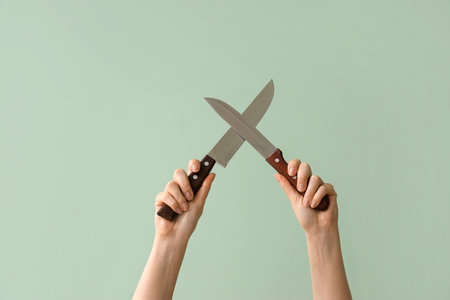 Woman with kitchen knives on green backgroundの写真素材