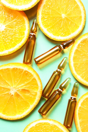Ampoules with vitamin C and orange slices on green backgroundの写真素材
