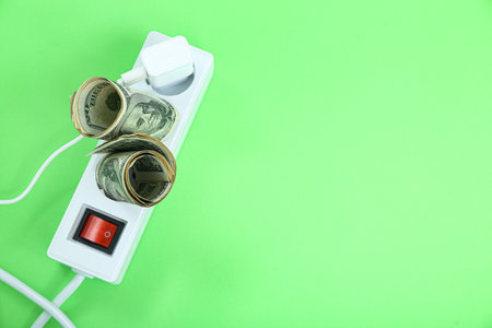 Power socket with plug and dollar banknotes on green backgroundの写真素材