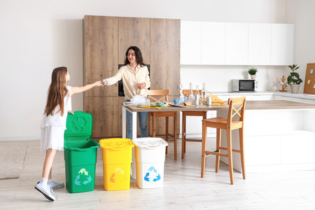 Little girl with her mother sorting garbage in kitchenの写真素材