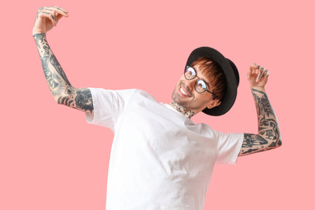 Young tattooed man dancing against pink backgroundの写真素材