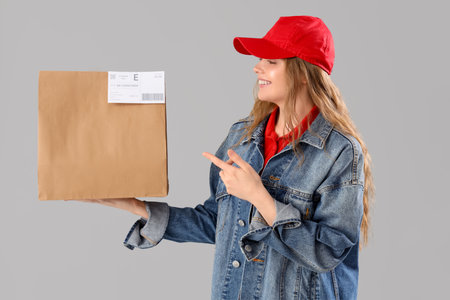 Beautiful young woman holding paper bag on gray background. Food deliveryの写真素材