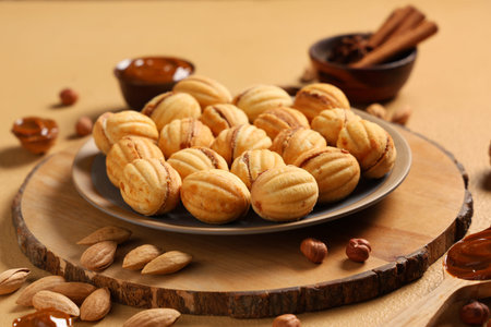 Tasty walnut shaped cookies with boiled condensed milk, almonds and hazelnuts on beige table,...