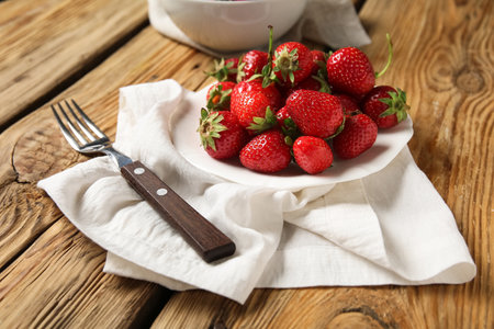 Plate with fresh sweet strawberries on wooden backgroundの写真素材