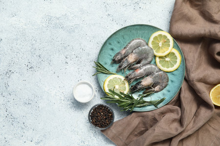 Plate with fresh raw shrimps, lemon and rosemary on white background