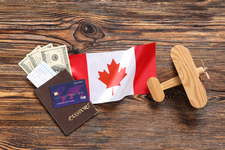 Canadian flag, toy plane, money and passport on wooden backgroundの写真素材