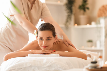 Young woman getting massage on couch in spa salonの写真素材