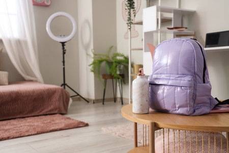 Lilac backpack with bottle of water on table in children's bedroom, closeupの写真素材