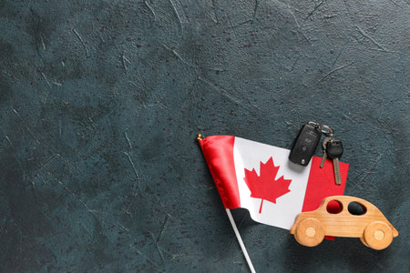 Wooden car, keys and Canadian flag on color backgroundの写真素材