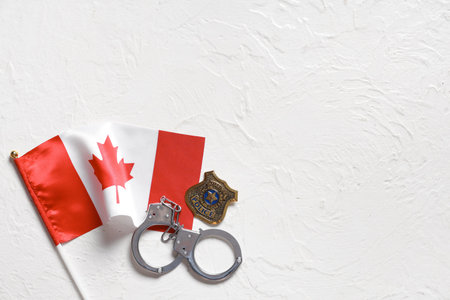 Police badge, handcuffs and Canadian flag on light background