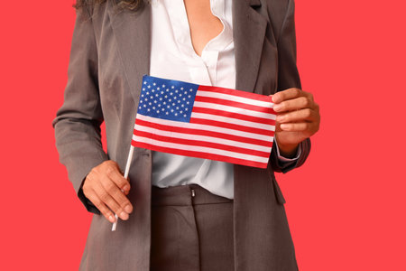 Beautiful young African-American businesswoman with USA flag on red background, closeupの写真素材