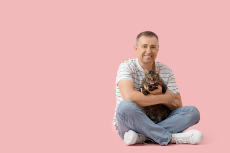 Mature man with cute cat sitting on pink backgroundの写真素材