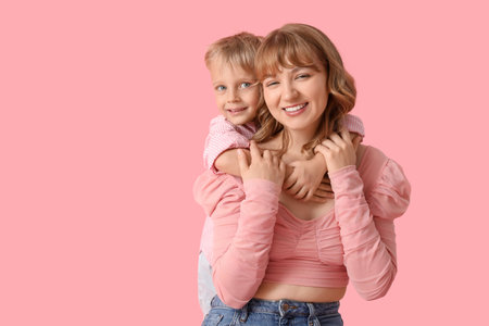 Happy mother and her little son hugging on pink backgroundの写真素材