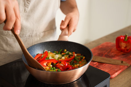 Young man frying vegetables in kitchen, closeupの写真素材