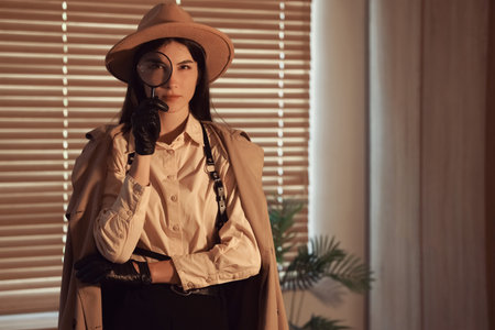 Female spy with magnifier in office at nightの写真素材