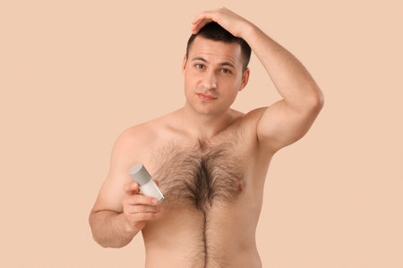 Handsome young man with deodorant on beige backgroundの写真素材