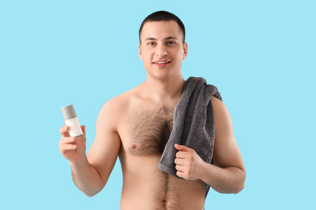 Handsome young man with deodorant and towel on blue backgroundの写真素材