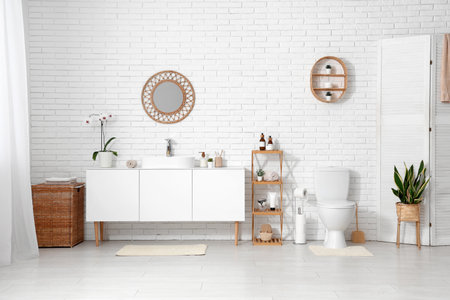 Interior of restroom with toilet bowl, shelving unit and chest of drawers with sinkの写真素材