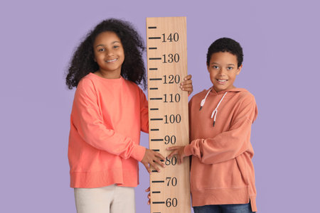 Little African-American children with stadiometer on lilac backgroundの写真素材