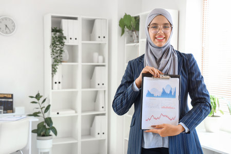 Beautiful Muslim businesswoman with clipboard in officeの写真素材