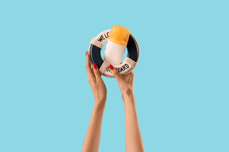 Female hands with decor lifebuoy and sunscreen cream on blue background