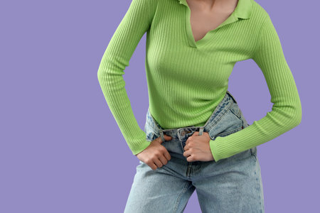 Beautiful young woman in stylish jeans on purple background, closeup