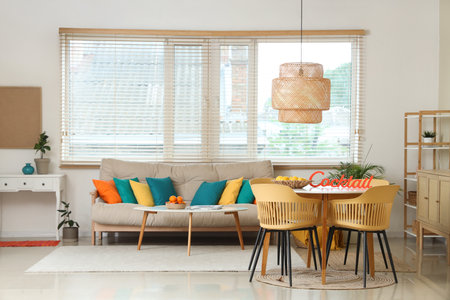 Interior of stylish living room with cozy sofa, basket with fruits on dining table and windowの写真素材