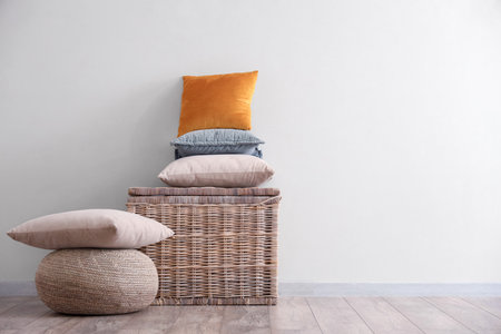 Wicket basket with stack of pillows near white wallの写真素材