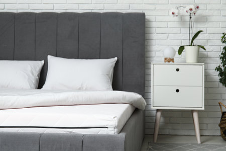 New orthopedic mattress with blanket on stylish bed in room, closeupの写真素材