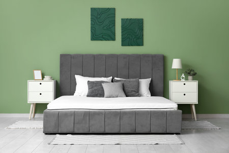 New orthopedic mattress on stylish bed near green wall in room
