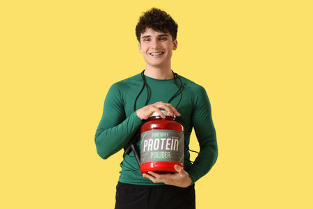 Sporty young man with protein powder on yellow backgroundの写真素材
