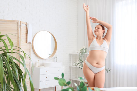 Beautiful plus size woman stretching in bathroomの写真素材