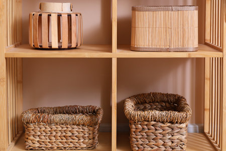 Shelving unit with braided baskets near beige wall in roomの写真素材