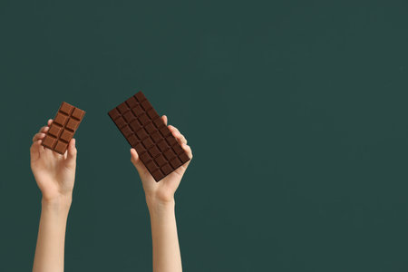 Female hands with different sweet chocolate on green backgroundの写真素材
