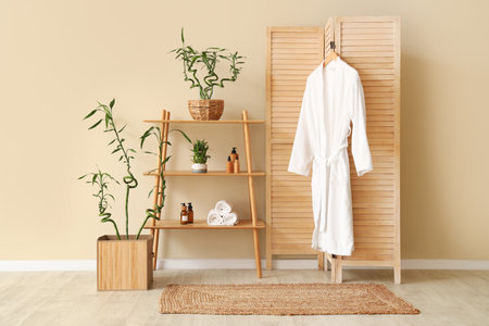 Folding screen with shelving unit and hanging bathrobe near beige wallの写真素材