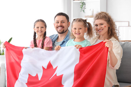 Happy family with flag of Canada sitting on sofa at homeの写真素材