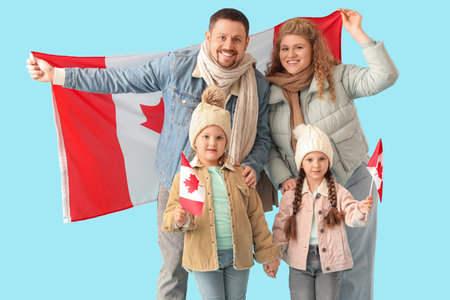 Happy beautiful family with flags of Canada on blue backgroundの写真素材