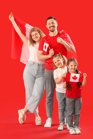 Happy beautiful family with flags of Canada on red backgroundの写真素材
