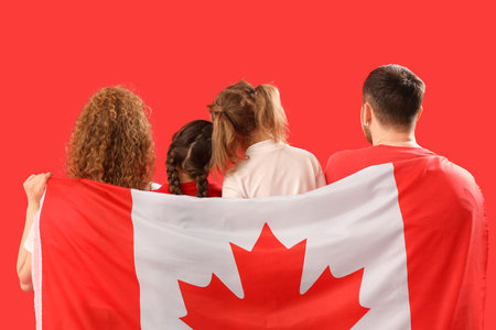 Beautiful family with flag of Canada on red background, back viewの写真素材