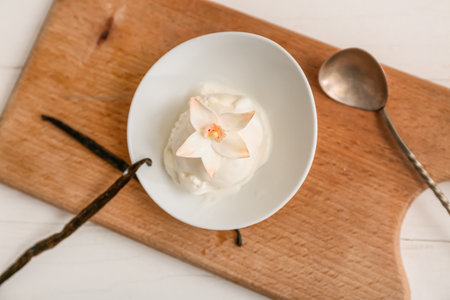 Bowl of sweet vanilla ice-cream ball with flower and sticks on white wooden tableの写真素材
