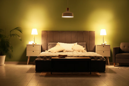 Stylish interior of bedroom with glowing lamps late in eveningの写真素材