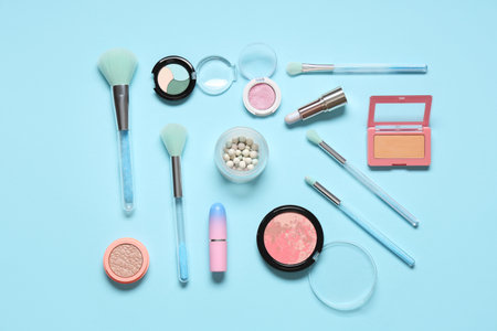 Stylish makeup brushes with cosmetic products on blue backgroundの写真素材