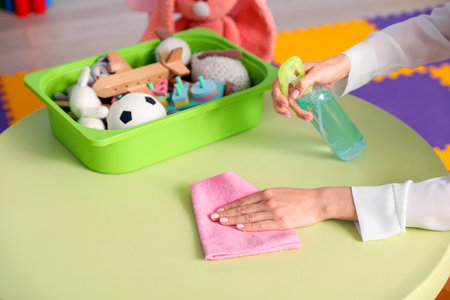 Female nursery teacher cleaning table in kindergarten, closeupの写真素材