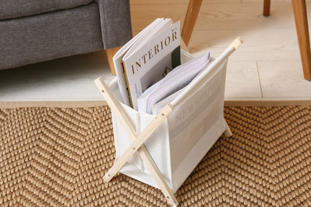 Black armchair and storage basket with magazines in living room, closeup