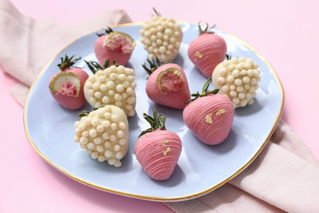 Plate with chocolate covered strawberries on pink background