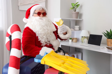 Santa Claus with cocktail and suitcases at home. Christmas in Julyの写真素材