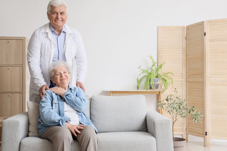 Senior woman with doctor sitting on sofa at homeの写真素材